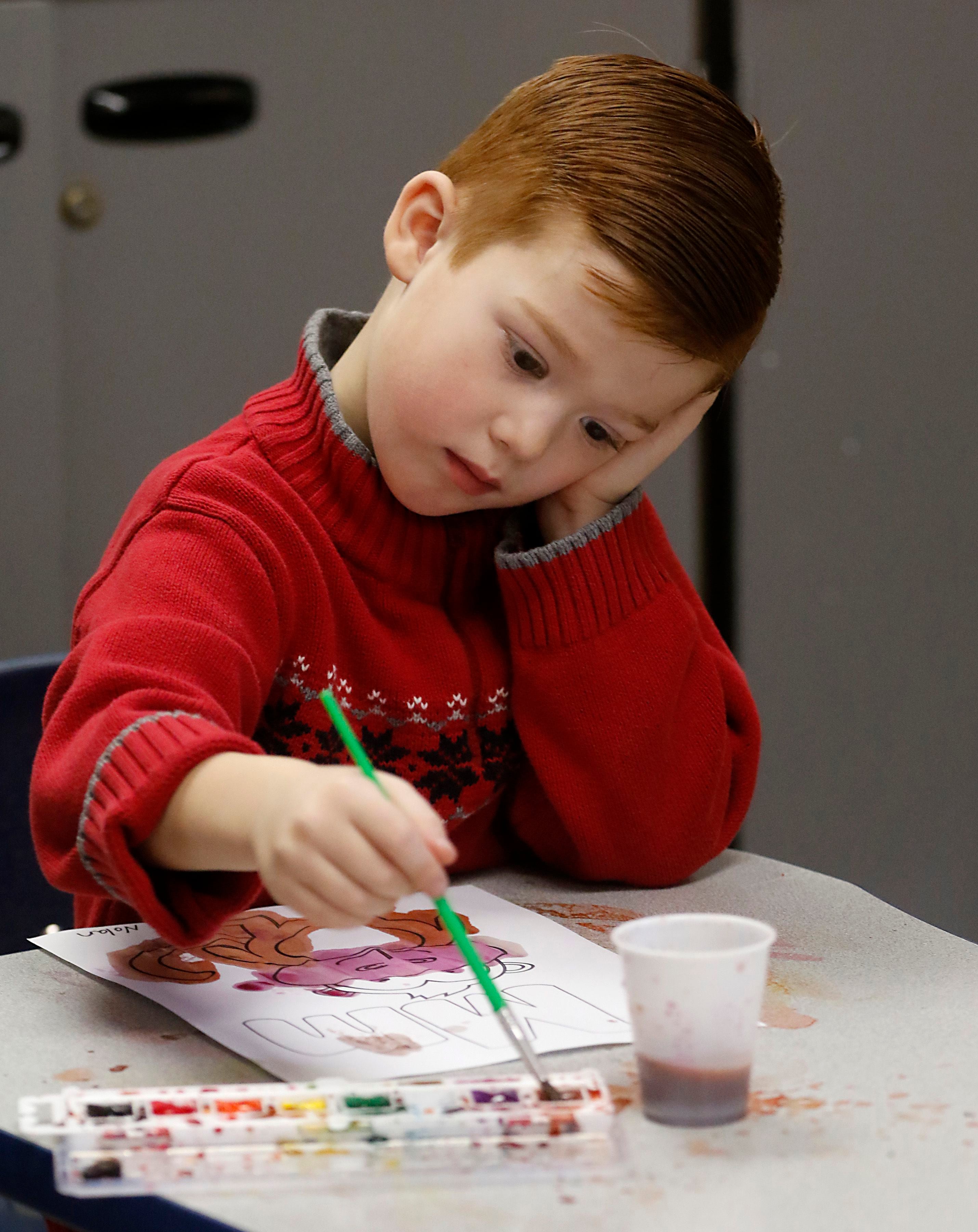 Nolan Beres paints the letter M on Thursday, Dec. 14, 2023, during class at Zion Lutheran Church and School in McHenry.