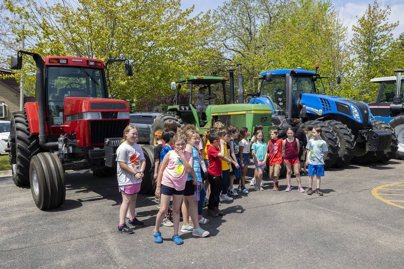 Lincoln School third graders pose in front of tractors at Sterling High School’s FFA Farmapalooza Thursday, May 11, 2023.