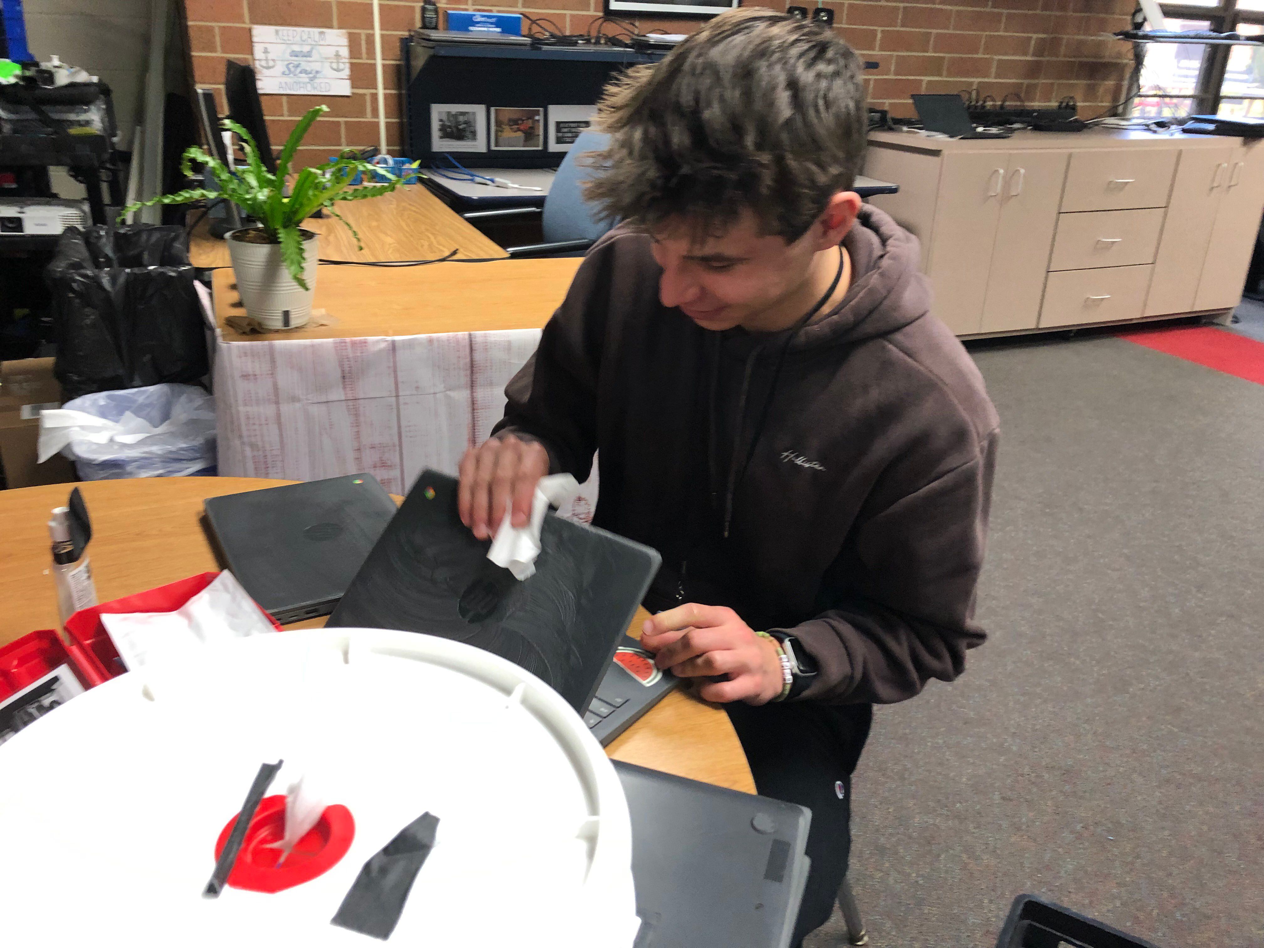 Huntley High School senior Logan Borzych wipes off a Chromebook Dec. 11, 2023. Borzych participates in the school's help desk program.