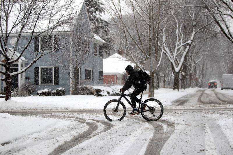 A bicycle rider travels through the snow in Glen Ellyn on Tuesday, Jan. 9, 2024.