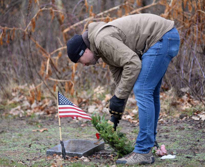 Luke Becker of Oregon, places a wreath at a veteran's grave during the Wreaths Across America event at Daysville Cemetery. east of Oregon, on Saturday, Dec. 16, 2023. Luke and his daughters, Lana,   Aven and Remy helped at the event.
