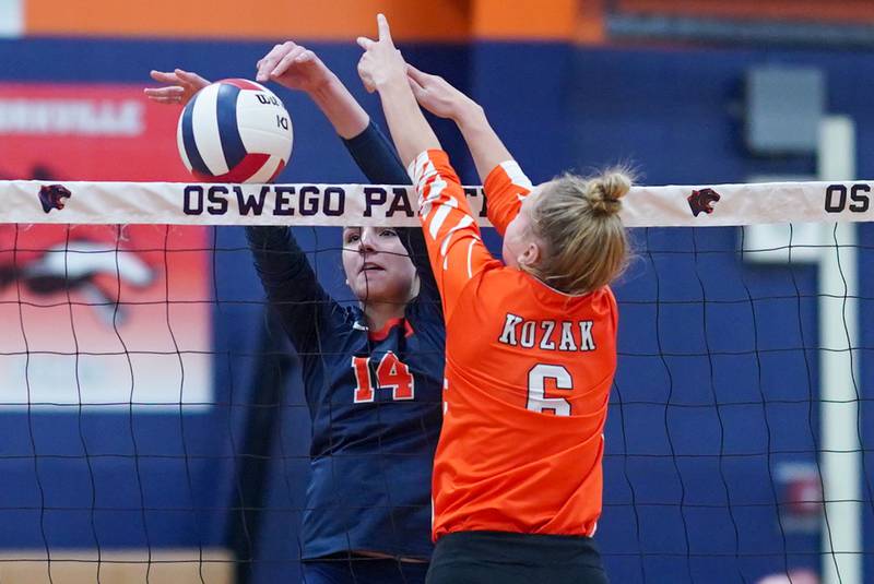 Oswego’s Mia Jurkovic (14) defends the net against a dink attempt by Minooka's Kendall Kozak (6) during a volleyball match at Oswego High School on Thursday, Oct. 3, 2024.