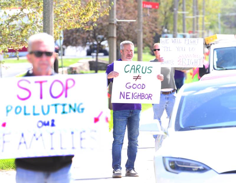 Former La Salle alderman Mark Schneider (center) holds a sign that reads "Carus Good Neighbor" while attending "Protest Carus Negligence" outside Carus headquarters across from the Westclox building on Friday, April 21, 2023 in Peru.