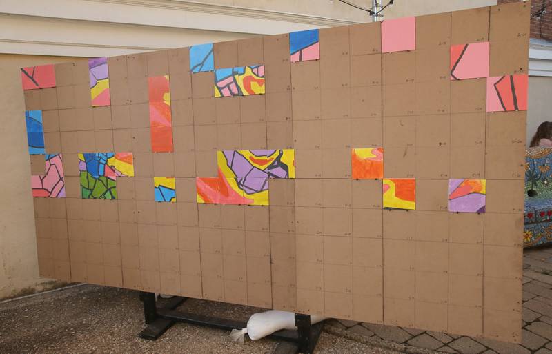 A large mural depicted of a torch was constructed paint a tile for the community mural project with the Princeton Public Arts Commission on Friday, June 20, 2025 downtown Princeton. The new mural will be displayed in the "Prairie Dreams" alleyway next to Fawcetts Pharmacy on South Main Street in Princeton.  “Prairie Dreams” is a living room grouping of mosaic-clad furniture (sofa, table and chairs) set under cloth sails and string lights along The Mary Uthoff Memorial Walkway.