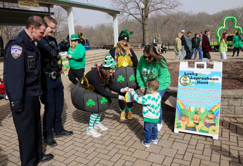 Shay Remus and Samantha Sendra of Yorkville Parks & Recreation give Jameson Corey a treat before the St. Patrick's Day Parade in Yorkville on Saturday, March 15, 2024, as Andrew Camis and Patrick McMahon of the Yorkville Police department (far left) and Jameson’s mom, Monica Corey (right) look on.