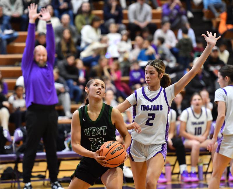 Downers Grove North’s Eva Yerkovich (2) defends against Glenbard West’s Mya Austin as Trojan coach Stephan Bolt (right) gives a hands up signal during a game on January 17, 2026 at Downers Grove North High School in Downers Grove .