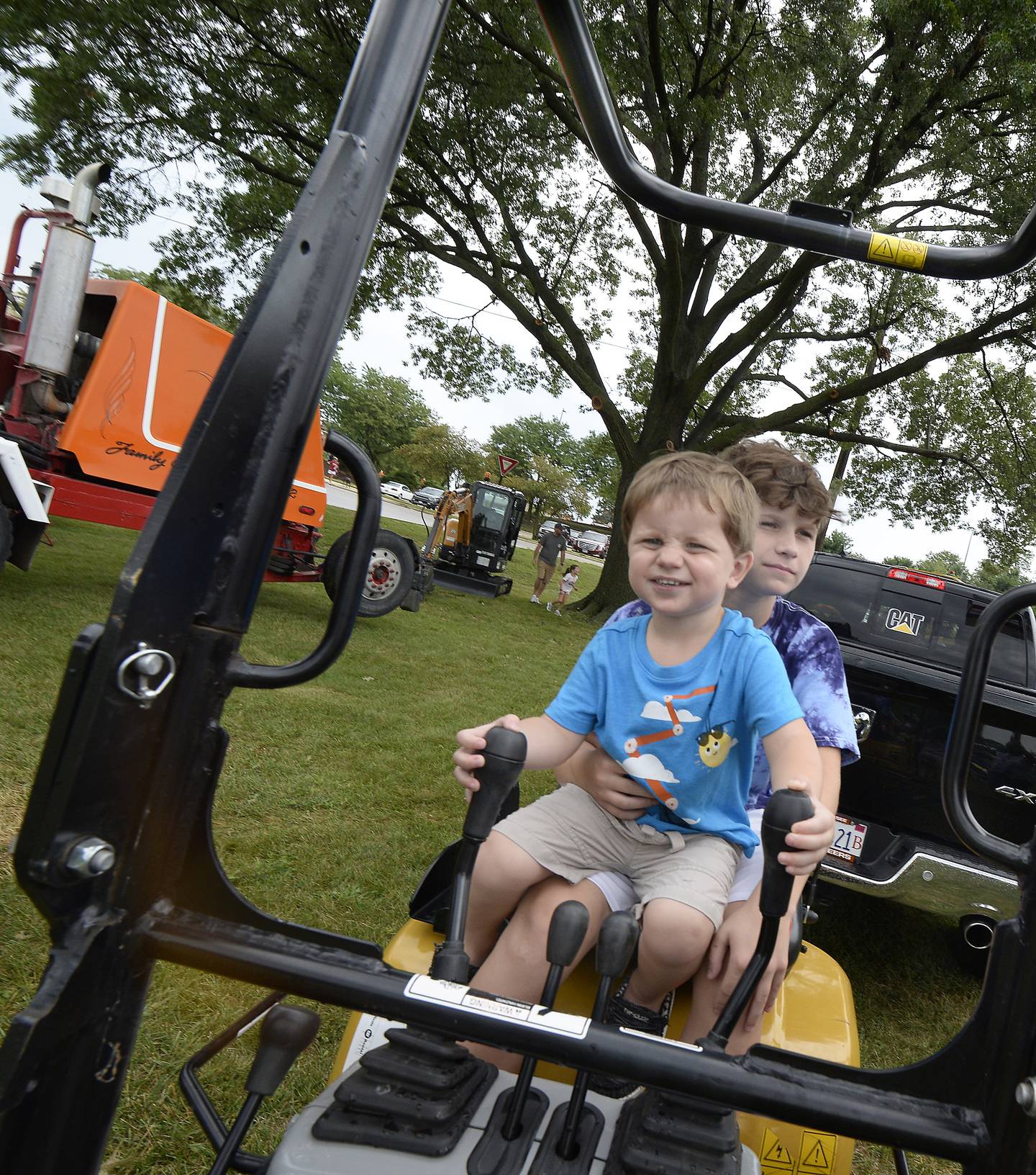 Brothers John and Michael Poggi pretend to operate a mini xcavator Sunday, Aug. 7, 2022, during the touch a truck event in Ottawa as part of Friendship Days.