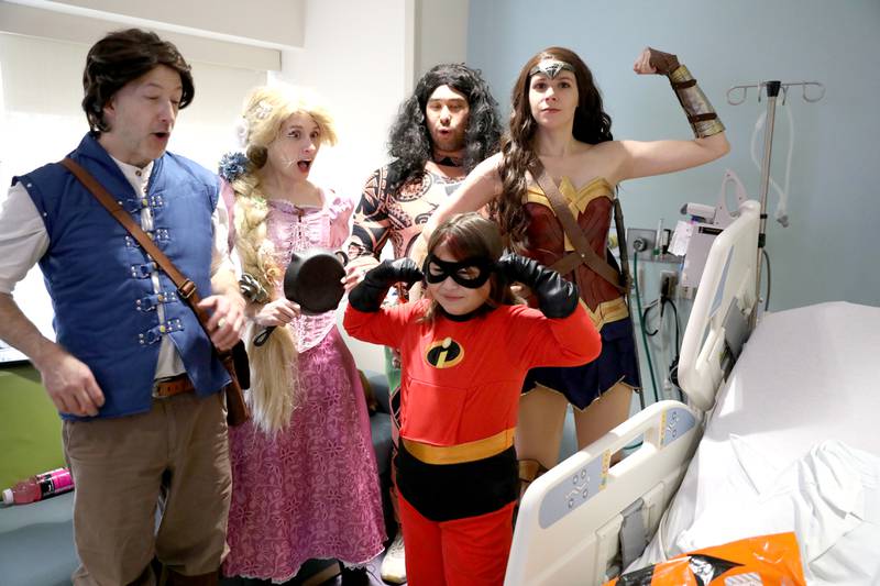 Miaah Servin, 8, of Batavia gets a visit from (from left) Scott Eckelberry as Flynn, Jen Watson as Rapunzel, Michael Nishimura as Maui and Abbo Rago as Wonder Woman during a Halloween visit to the pediatric intensive care unit of Northwestern Central DuPage Hospital in Winfield on Tuesday, Oct. 31, 2023.