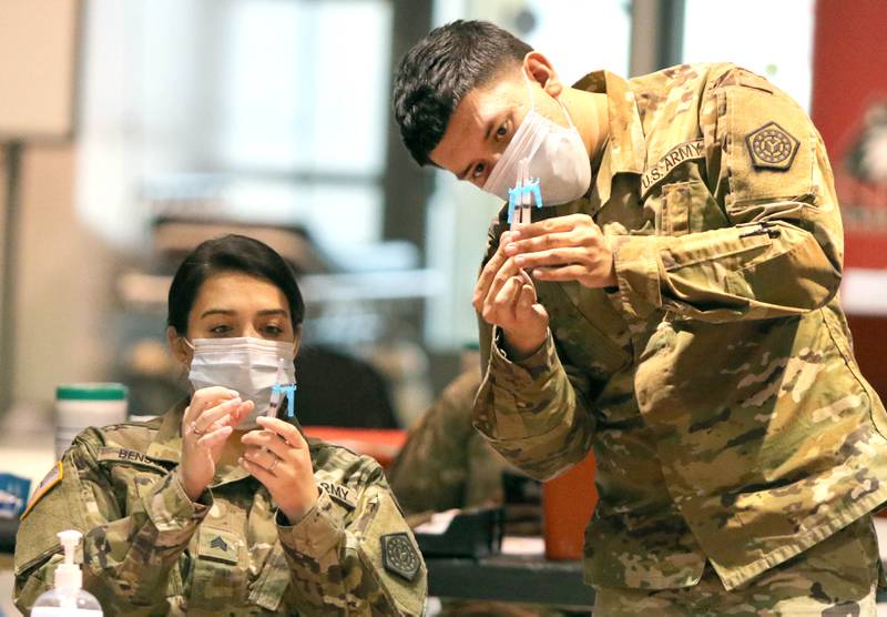 Members of the Illinois National Guard check their COVID-19 vaccines Wednesday at the Convocation Center at Northern Illinois University in DeKalb.