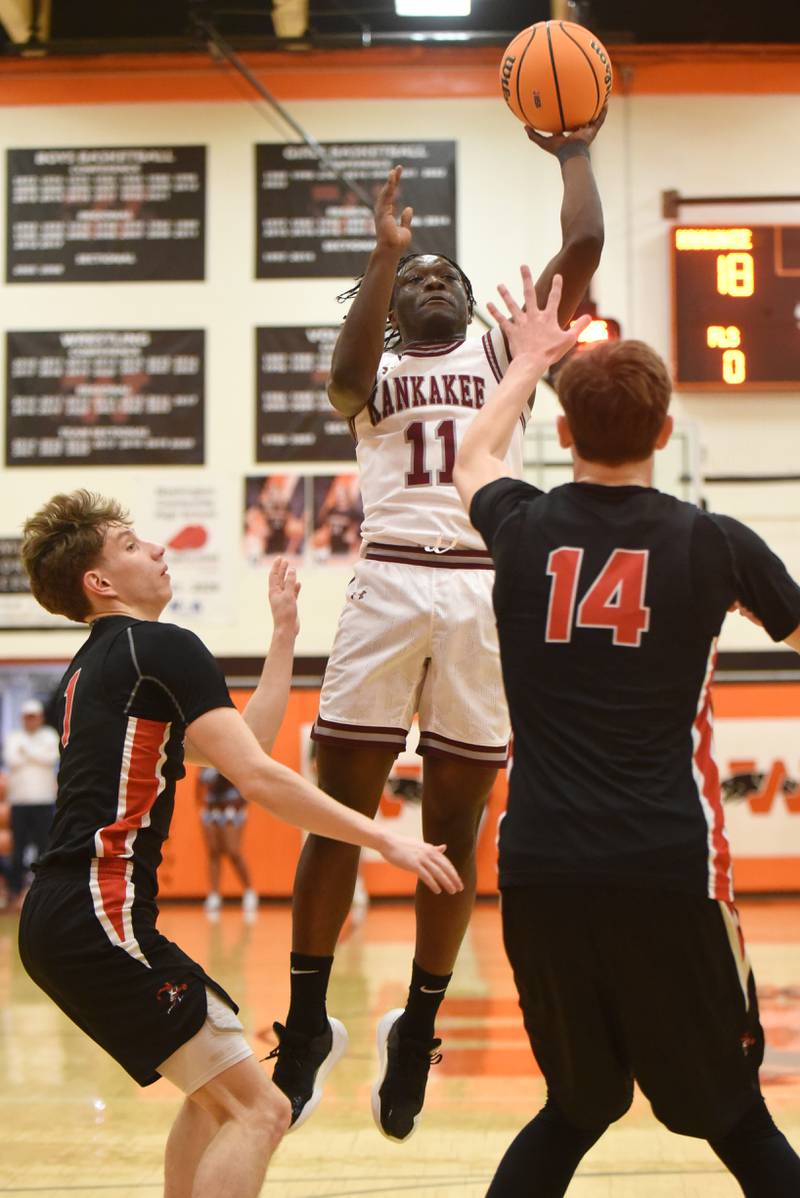 Kankakee's Jordan Davis (11) takes a shot as Metamora's Ashton Grieves, left, and Jonah Funk defend during the IHSA Class 3A Washington Sectional semifinals Tuesday, March 4, 2025.