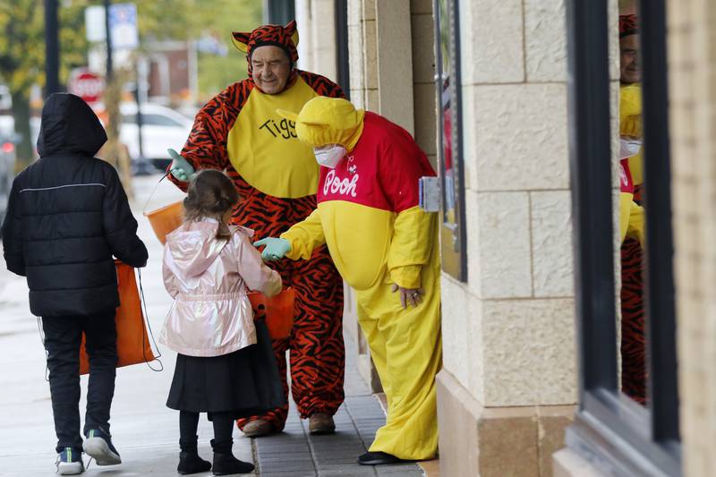 From left: Alexius Pelaez, 10, and sister Estella Pelaez, 6, go trick-or-treating at the Raue Center for the Arts with volunteers Jim and Priscilla Graziano, all of Cary, during the Halloween Handout event Friday, Oct. 29, 2021, in Crystal Lake.