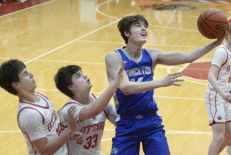 Princeton’s Grady Thompson gets by Ottawa’s Payton Knoll and Cooper Knoll for a layup in the 1st period in Kingman Gymnasium on Saturday, Jan. 21, 2023 at Ottawa High School.