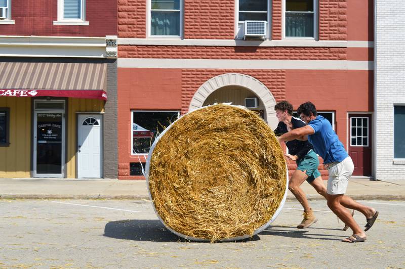 Tyler Willman, foreground, and Levi Schuler, both of Pine Creek, race to push a 700-pound straw bale across the finish line during StrawFest Day in Mt. Morris on Aug. 27. The pair ultimately won the straw bale races, which were just one activity in the final celebration of the U.S. National Straw Sculpting Competition.