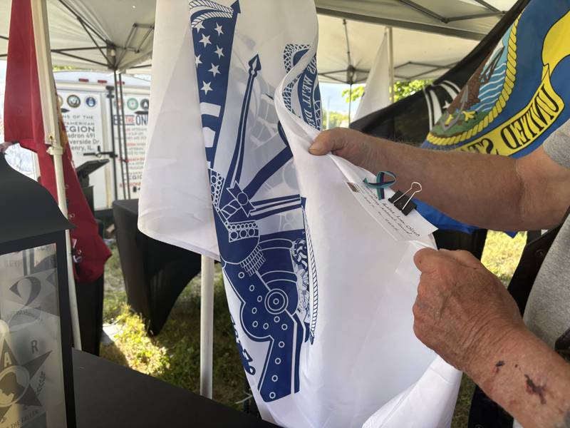 Keith Lambert holds up a flag with a veteran's name pinned to it at the Field of the Fallen in Cary May 23, 2026.