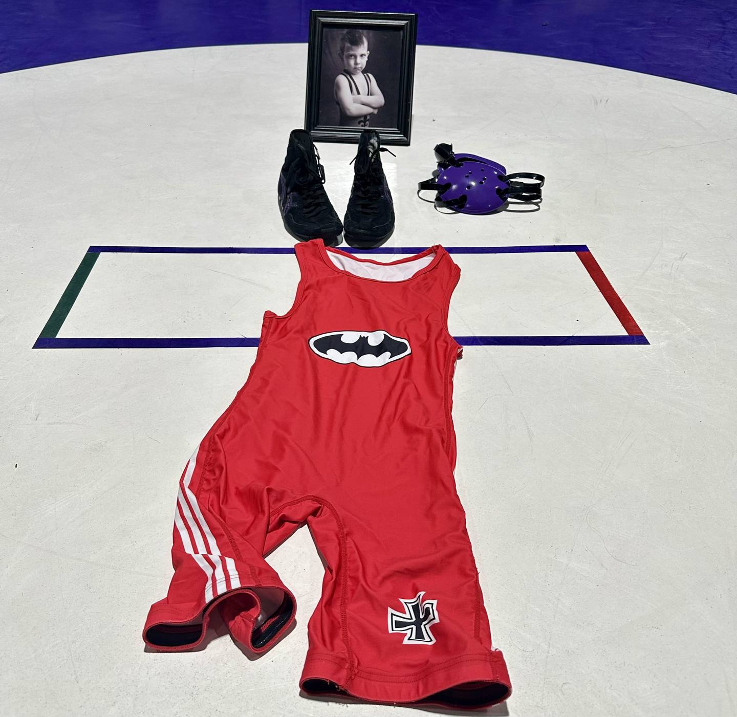 A singlet, wrestling shoes, head gear and a framed photo of Deegan Kirschke were placed inside the center circle of the wrestling ring at the end of Hampshire's dual against Dundee-Crown on Thursday.