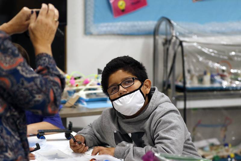 Coventry Elementary School fifth grade student Oscar Sangabriel-Landa watches as STEM teacher Leslie Wise, left, helps students with building a robotic vehicle from a Vex Kit during in-person learning at Coventry Elementary School on Wednesday, Sept. 29, 2021 in Crystal Lake.   The new kits were available to use last year but using shared materials was not possible until this school year.