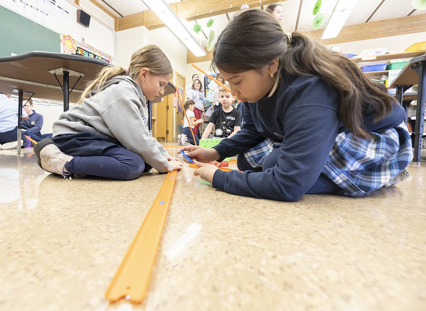 Dixon St. Anne’s students build a track to race their toy cars down Thursday, March 6, 2025. The challenge was to learn how to make their cars go faster with added weight and track changes.