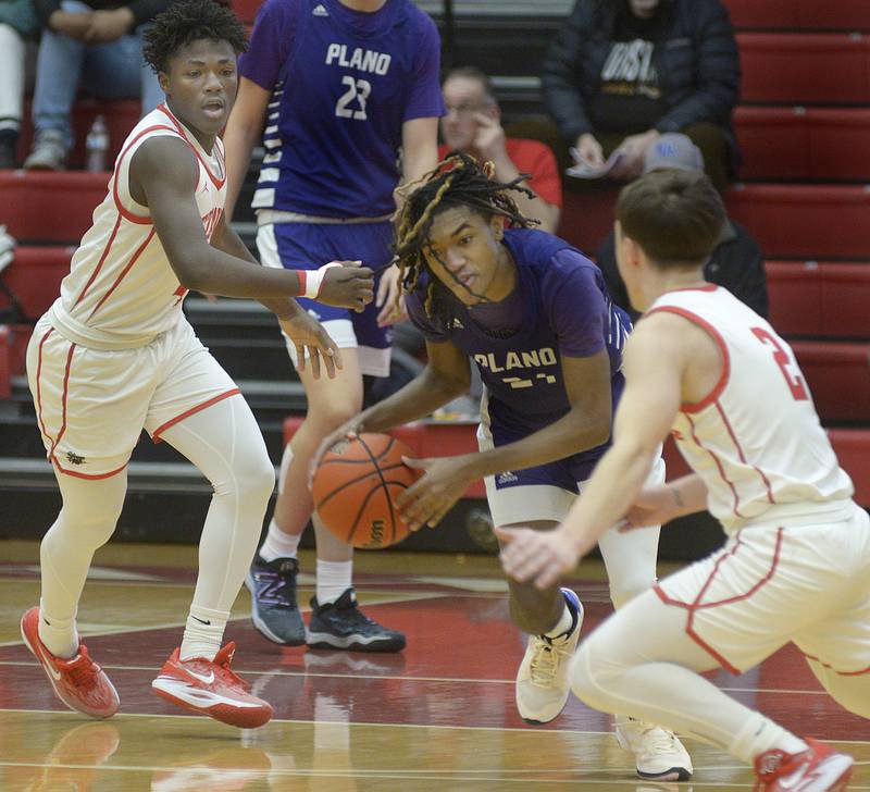 Plano’s Ta’ron McGowan (center) drives past Ottawa’s Keevon Peterson (left) and Huston Hart (2) on a drive during the second quarter Tuesday, Dec. 12, 2023, at Kingman Gym in Ottawa.