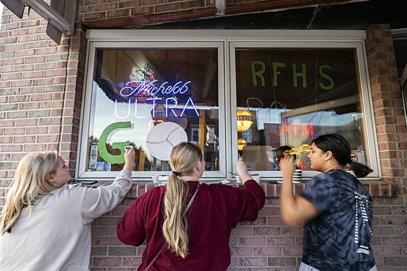 Amya Velazquez (left), Addy Watts and Taylor Reyna put some color on the windows of Corner Tap Monday, Nov. 6, 2023 in Rock Falls. The downtown got a fresh coat of green as the volleyball team and supporters decorated it ahead of the team’s trip to state.