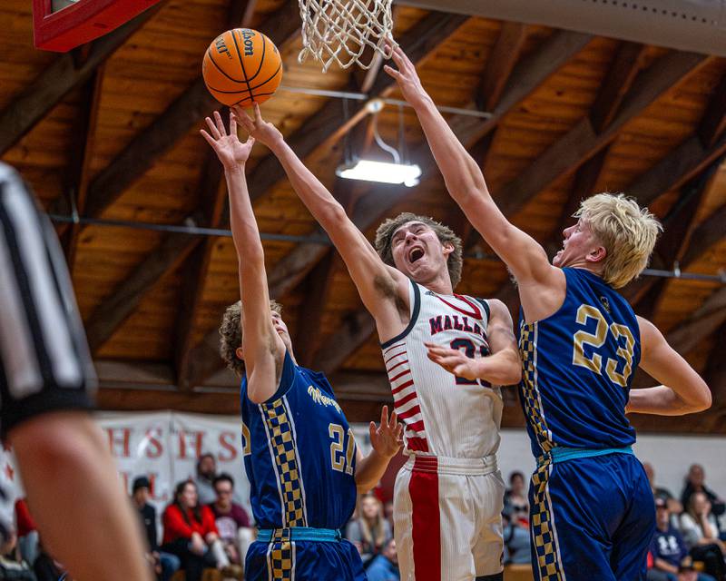 Henry-Senachwine's Carson Rowe (21) lays up ball as Marquette's Griffin Dobberstein (21) and Luke McCullough (23) leap to contest shot on Friday, Feb. 13, 2026 at Henry-Senachwine High School in Henry.