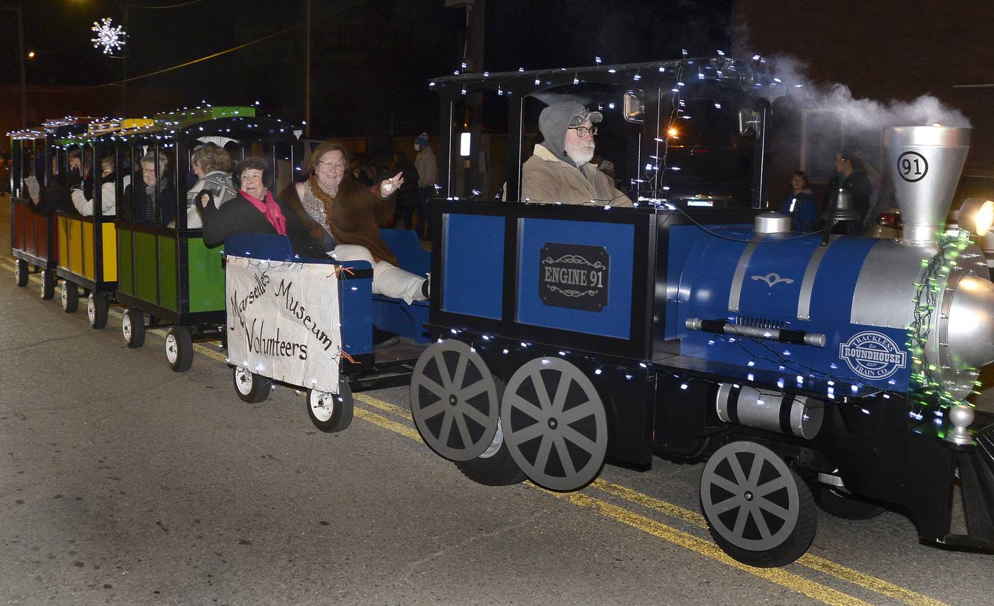 Seattle Sutton waves to the parade crowd Saturday, Dec. 4, 2021, as she rides in the Marseilles Museum train as if puffs along Main Street during the annual Holiday Magic Lighted Santa Parade.