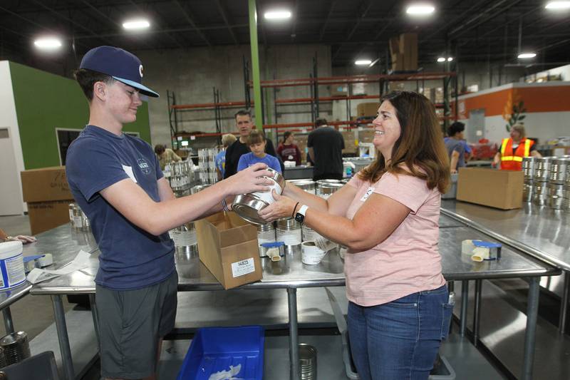 Carson Young, 16, of Antioch works with his mother, Susan, labeling cans of green beans and boxing them up at the Northern Illinois Food Bank on August 19th in Lake Forest. The North Suburban Center recently celebrated it’s one-year anniversary at this location.  
Photo by Candace H. Johnson for Shaw Local News Network