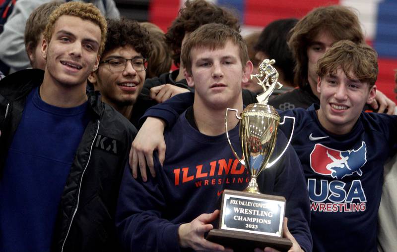 McHenry’s Chris Moore poses with the Fox Valley Conference championship trophy after the Warriors clinched an outright title with a win over Dundee-Crown in varsity wrestling at Carpentersville Thursday night.