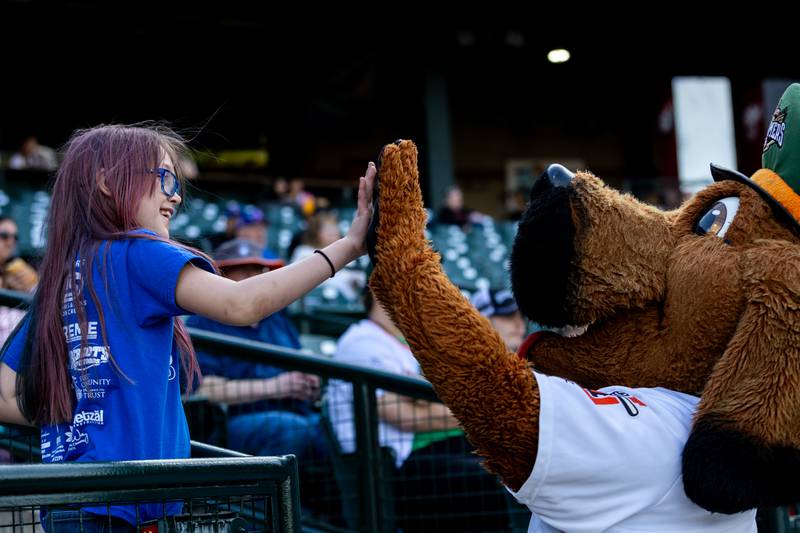 Frankfort resident Lorraine Halloran high fives Spikes during during the home opener of the Joliet Slammers on Friday, May 8, 2026.