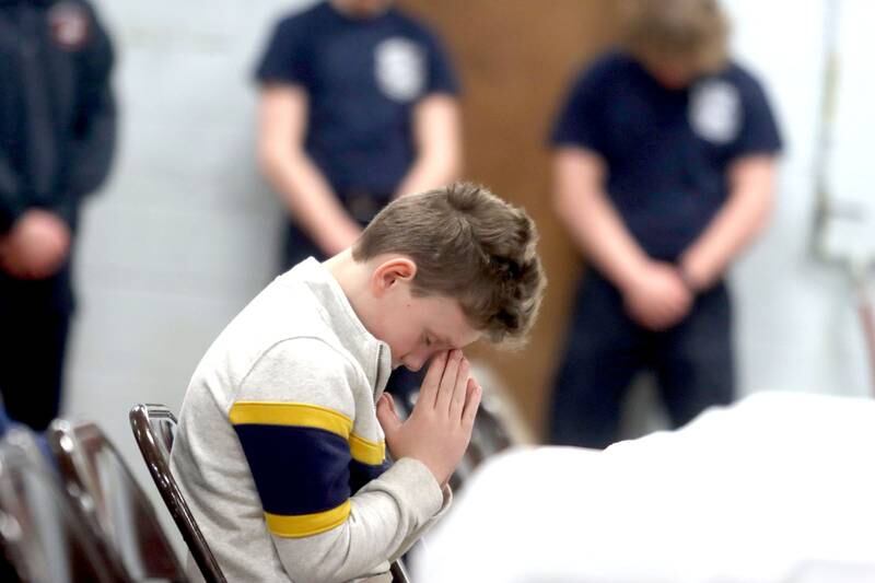 Anthony Olczyk, 8, of Oswego pauses in prayer during a remembrance Saturday at Wonder Lake Fire Protection District Station 2 on the 40th anniversary of a midair military jet explosion that happened over the small, rural area northeast of Woodstock. Olczyk’s grandfather and 26 others lost their lives as the plane exploded midair at 9:11 p.m. on March 19, 1982, its flaming pieces raining over a 2-mile area near Greenwood. On board were more than two-dozen members of the Air Force Reserve and Air National Guard.