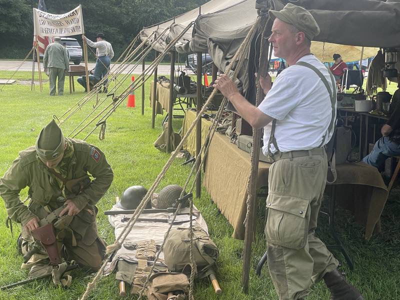 Tim Cook (right) looks off into the distance Saturday, Aug. 2, 2025, as James Dreska adjusts his holster.
