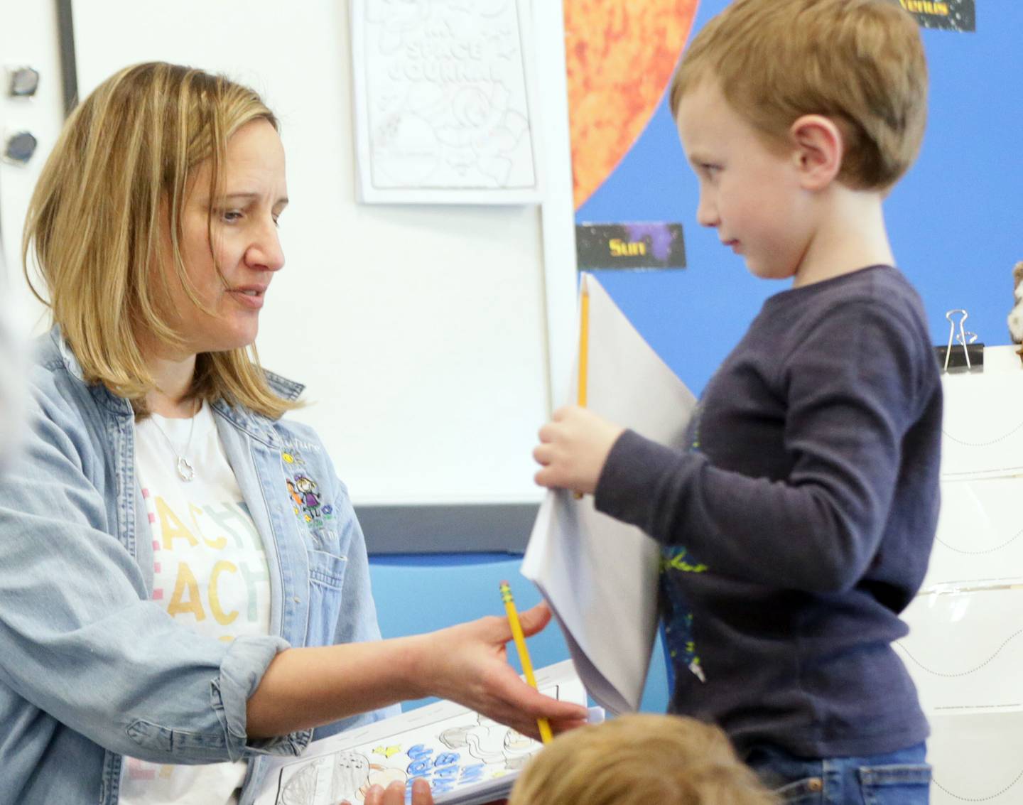 Mrs. Karin Kummer, a kindergartener teacher at Waltham School looks over student Brody Grubar's papers on Tuesday, March 8, 2022 in Utica.