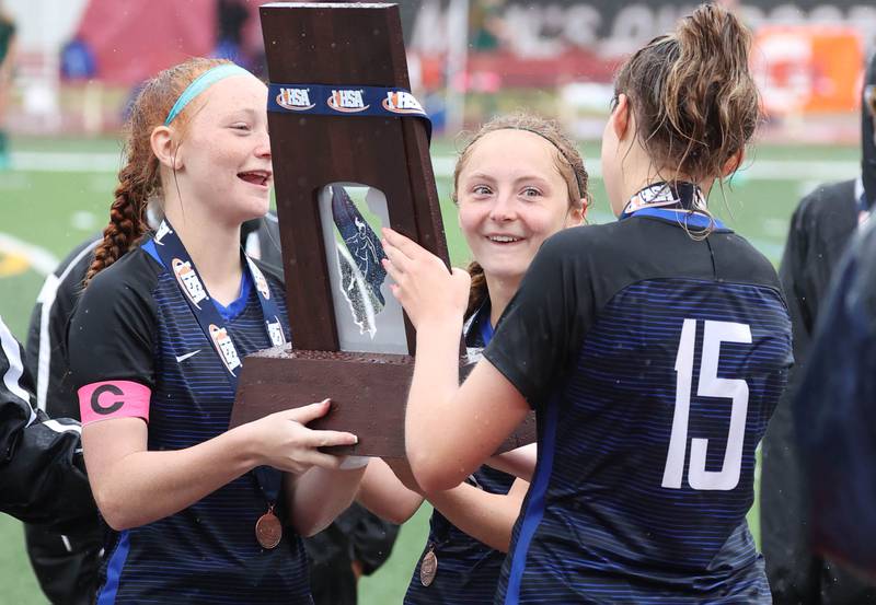Burlington Central players admire the state fourth place trophy Saturday, June 1, 2024, after their consolation match loss to Peoria Notre Dame at the IHSA Class 2A state soccer finals at North Central College in Naperville.