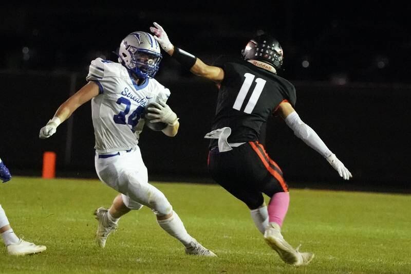 Woodstock's Stewart Reuter (34) carries the ball against Sandwich’s Nick Michalek (11) during a football game at Sandwich High School on Friday, Oct. 11, 2024.