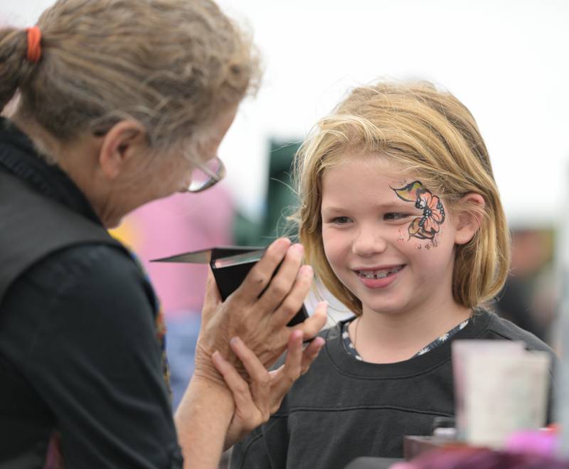 Savannah Rothstein, 8 of Elgin is all smiles as she views her completed face painting by Arlene Hughes of Fancy Face Art during the Campton Hills National Night Out on Tuesday, August 6, 2024.