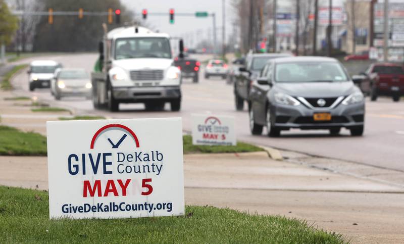 Cars travel Sycamore Road in DeKalb Tuesday, May 3, 2022, past signs reminding people to be generous during Give DeKalb County.
