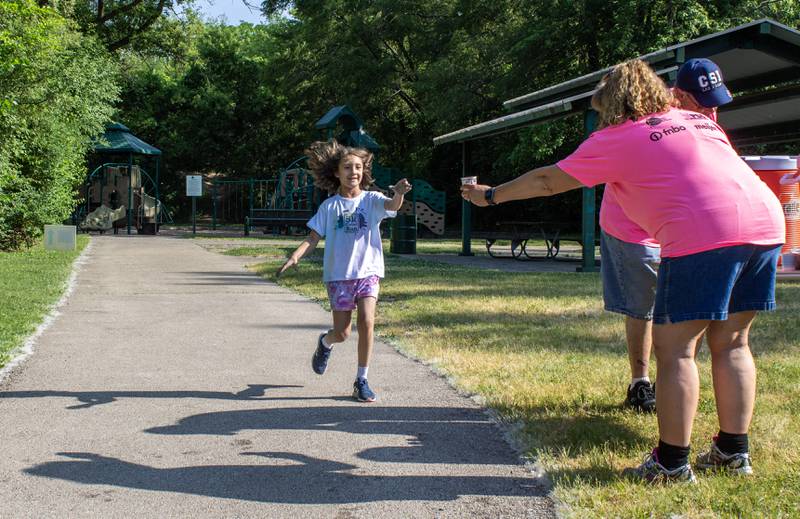 A runner grabs a cup of water at the second water station near the Sycamore Lake Rotary Park during CASA DeKalb County's annual 5K Color Run. The course circled around the park before following the path back to Sycamore Middle School on Saturday, June 3, 2023.