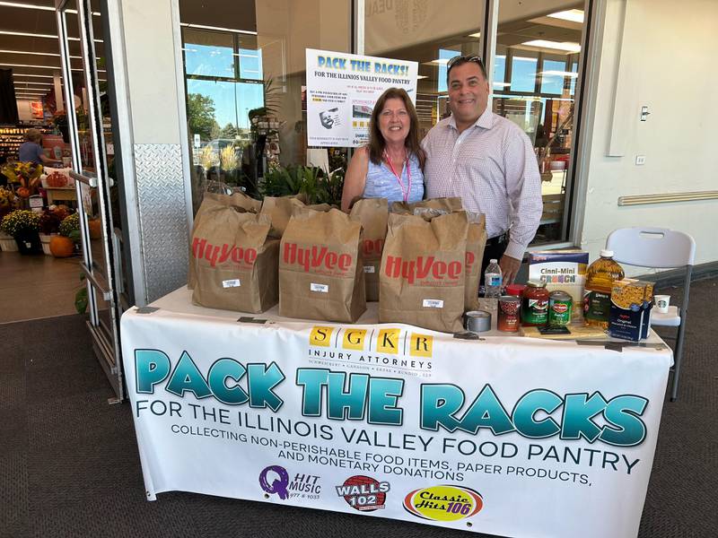Illinois Valley Food Pantry Director Mary Jo Credi, and Attorney Mike Krzak stand in front of Hy-Vee in Peru for the “Pack The Racks” event Friday, sponsored by Peru Hy-Vee, Schweickert, Ganassin, Krzak and Rundio Injury Attorneys and Shaw Local Radio.