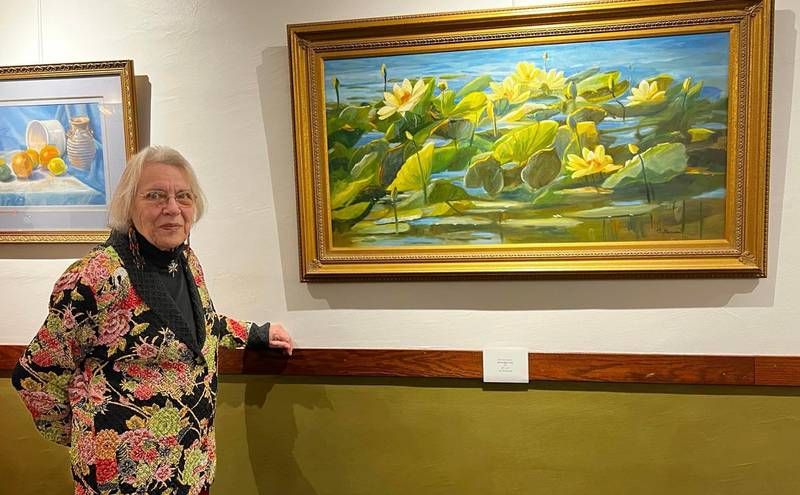 Artist Beverly Garcia standing in front of her artwork on display at Woodlawn Arts Academy.
