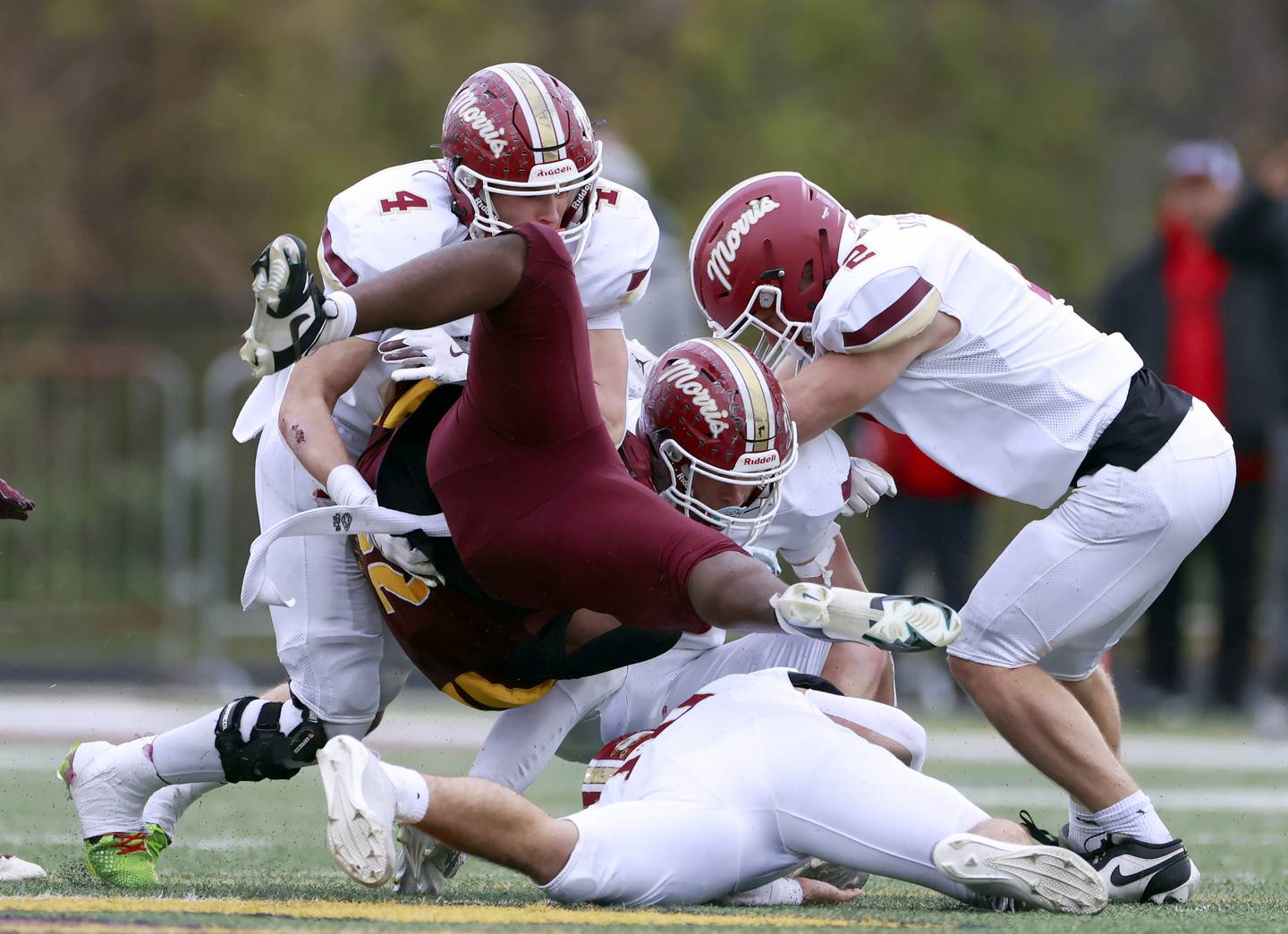 Montini's Isaac Alexander (28) is brought down by a host of Morris players including Mick Smith (4) and Bryce Varner (2) during the IHSA Class 4A semifinals football playoff game Saturday, Nov. 22, 2025 in Lombard.