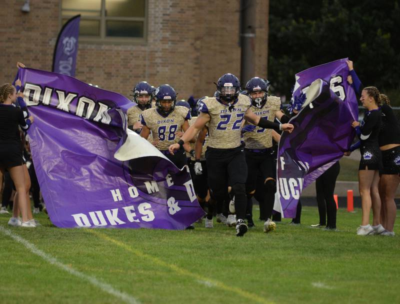Dixon's Devon Wallace (88) and Aiden Wiseman (22), lead the Dukes out on to AC Bowers Field At Dixon High School in their home opener against Rock Falls on Friday, Sept. 8, 2023.