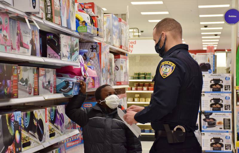 Zarain Frills of DeKalb, 8, talks to Chris Sullivan, a school resource officer with the DeKalb Police Department, about a scooter during the Heroes and Helpers event, held at the Target store in DeKalb Sunday, Dec. 12, 2021