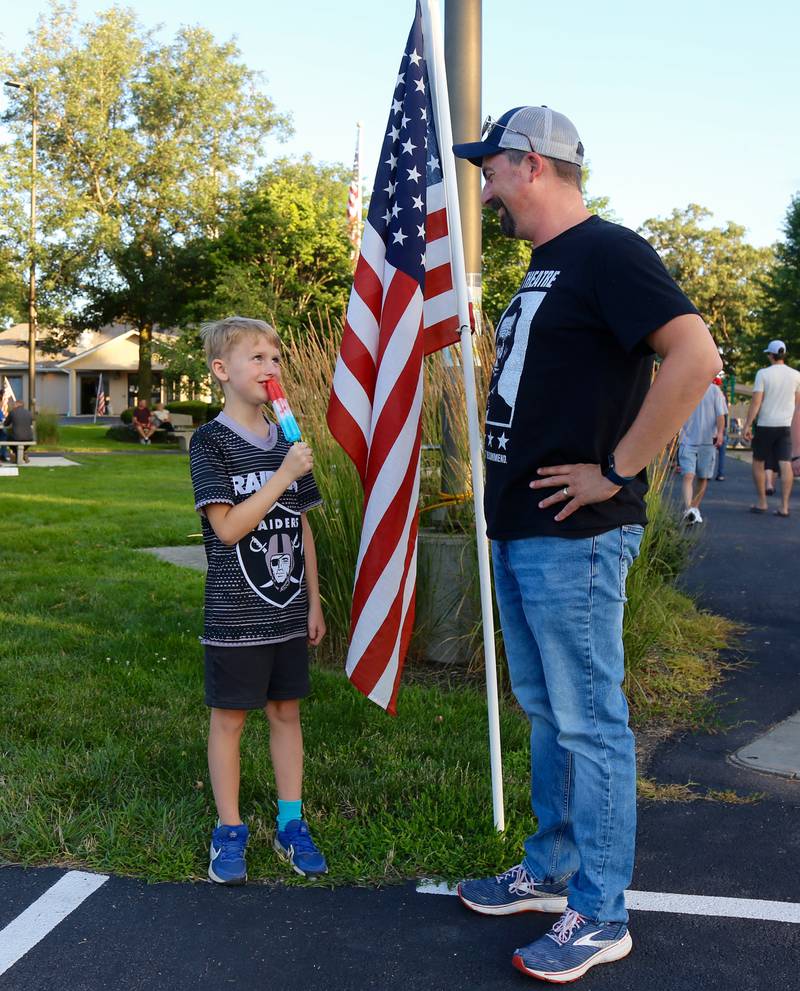 Rhys Wood of Sugar Grove enjoys a popsicle while his dad, Matt Wood, looks on before the Elburn Fireworks Show at Lions Park on Saturday, July 6, 2024 in Elburn.