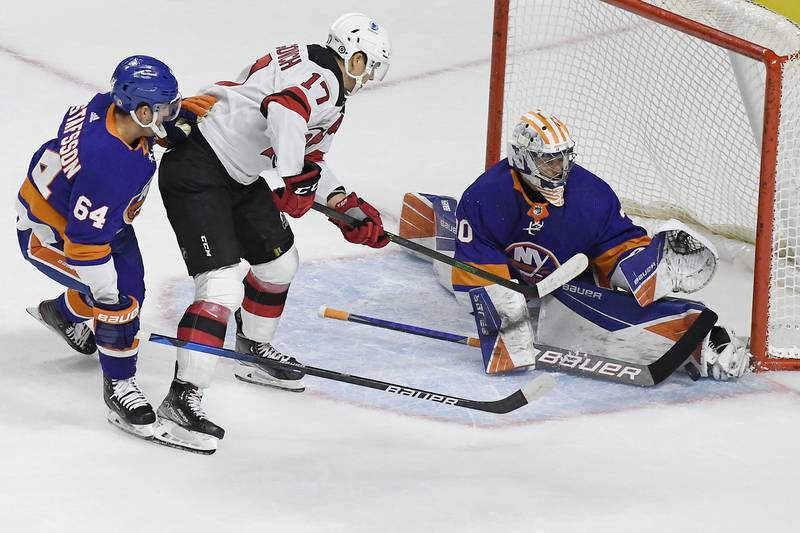 New York Islanders goalie Ilya Sorokin, right, stops a shot attempt from New Jersey Devils' Yegor Sharangovich as New York Islanders' Erik Gustafsson, left, defends, during an NHL preseason hockey game, Saturday, Oct. 2, 2021, in Bridgeport, Conn. (AP Photo/Jessica Hill)