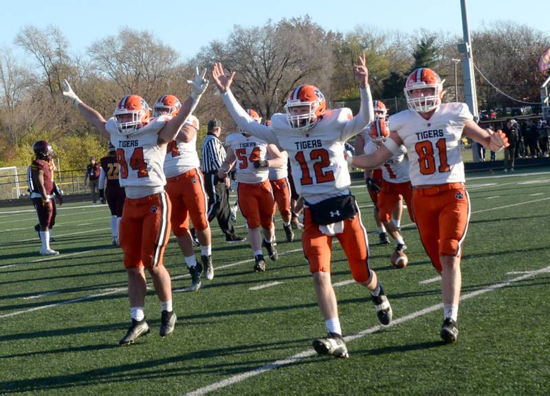 Byron's Kyle Jones (84), Ayden Shank (12), and Braylon Kilduff (81) run to the sideline to greet their teammates as time expires in the Tigers' win over Lombard-Montini in 3A football semifinals in Lombard on Saturday, Nov. 18, 2023.