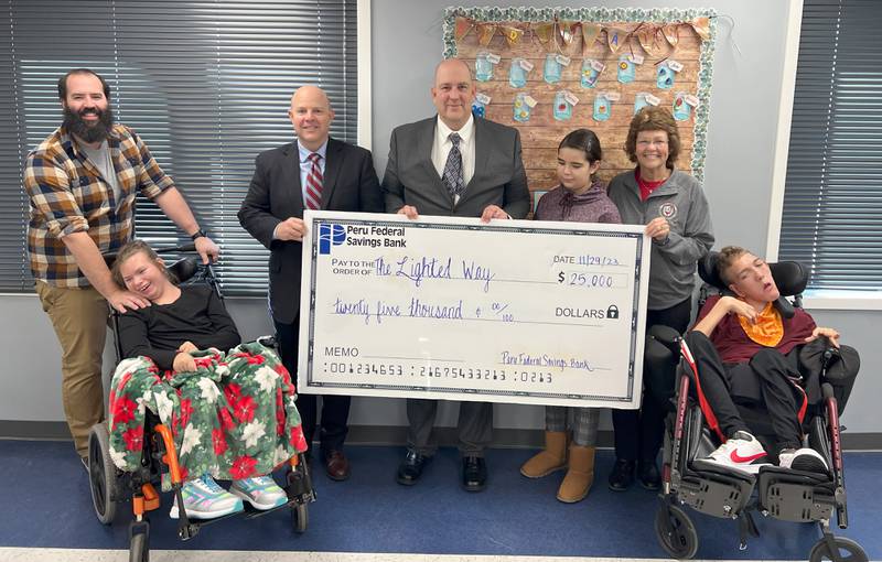 Peru Federal Savings Bank donated $25,000 to Lighted Way. (From left) Lighted Way Teacher Brandon Miller, student Alycia Lautwein, representatives of Peru Federal Savings Bank Chris Vaske and Eric Heagy, student Karina Vela, Lighted Way Executive Director Jessica Kreiser and student Decan Dejewski take part in the presentation.