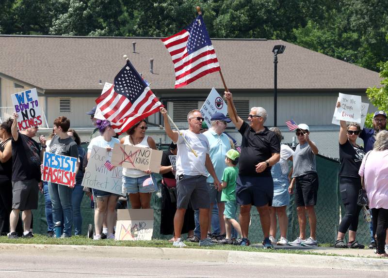 Protesters chant and wave flags along Sycamore Road Saturday, June 14, 2025, during a No Kings rally at Hopkins Park in DeKalb. The group was protesting the policies of President Donald Trump and his administration.