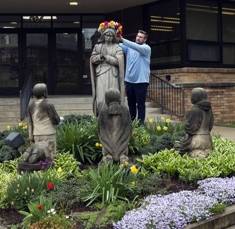 St. Mary’s school principal Luke Phillips adorns a statue of Mary with a crown of flowers Thursday, May 1, 2025, in Dixon. Rain kept the May Crowning ceremony inside the church at St. Patrick’s.