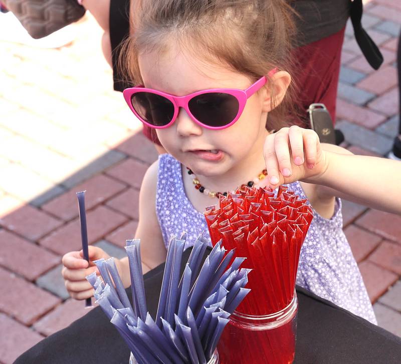 Melody Claar, 3, from DeKalb, has trouble deciding which flavored honey stick to get at the Willow Creek Honey booth Thursday, June 2, 2022, during the first DeKalb Farmers Market of the season at Van Buer Plaza in Downtown DeKalb.
