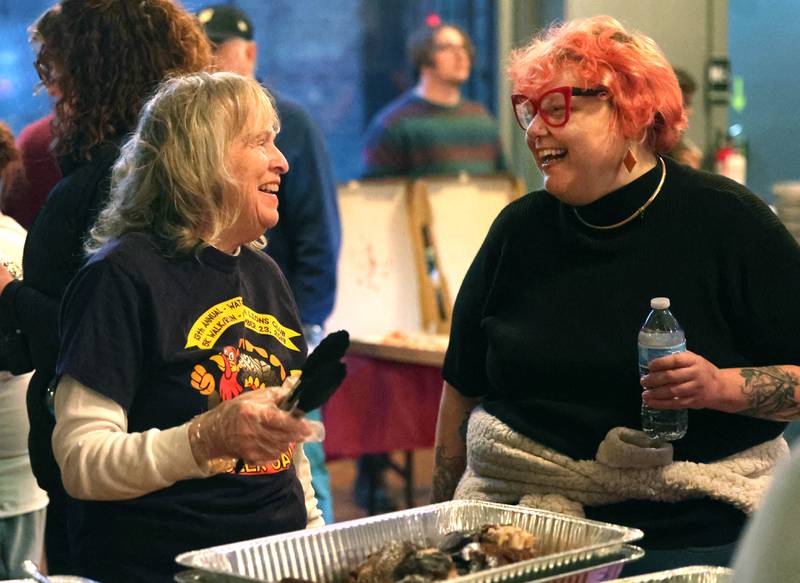 Volunteer Inge Nicklas, (left) from DeKalb, and Ash Rootes, executive director of DeKalb Mutual Aid, share a laugh Wednesday, Nov. 26, 2025, during A World of Thanks, Community Thanksgiving hosted by DeKalb Mutual Aid at the McCabe’s building in DeKalb.
