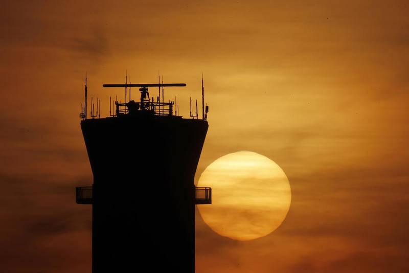 The sun sets behind the FAA control tower Tuesday at Chicago's Midway International Airport in Chicago. Southwest Airlines canceled all of its fights into and out of Midway International Airport, days after federal authorities closed the airport's control tower after technicians tested positive for the coronavirus.